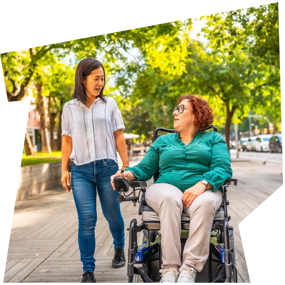Disabled woman in wheelchair outside with support worker